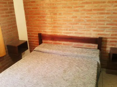 a bed in a room with a brick wall at Departamentos Flor de Loto in Mina Clavero