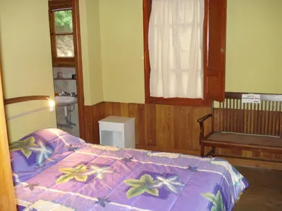a bedroom with a bed and a chair and a window at Lo de Lily in Embalse