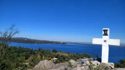a white cross on top of a hill with a lake at Lo de Lily in Embalse