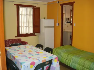 a kitchen with a table and a bed and a refrigerator at Lo de Lily in Embalse