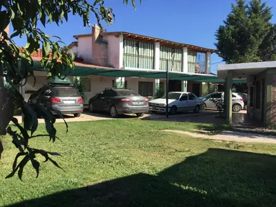 a building with cars parked in a parking lot at Aoniken Cabañas in Villa Cura Brochero