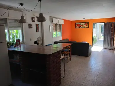 a kitchen and living room with orange walls and a bar at Hostel El Refugio de Las Aves in Santa Rosa de Calamuchita