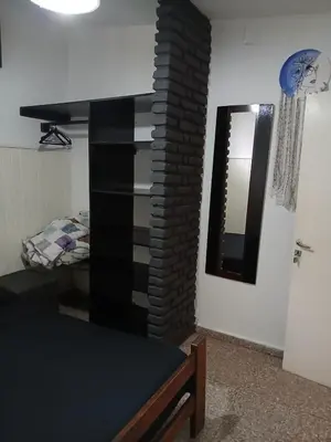 a living room with a black book shelf and a mirror at Hostel El Refugio de Las Aves in Santa Rosa de Calamuchita