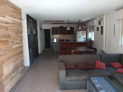 a living room with a couch and a kitchen at Hostel El Refugio de Las Aves in Santa Rosa de Calamuchita