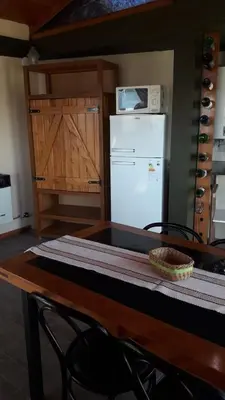 a kitchen with a table with a microwave and a refrigerator at Cabañas Doña Itati in Villa Carlos Paz