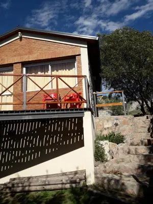 a house with a balcony with a table on it at Cabañas Doña Itati in Villa Carlos Paz
