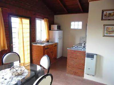 a small kitchen with a table and a refrigerator at Cabañas Doña Itati in Villa Carlos Paz