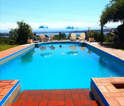 a blue swimming pool with chairs and umbrellas at Vistas Apart in Embalse