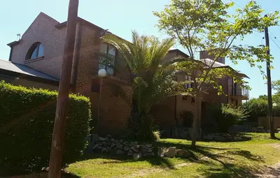 a house with a palm tree in front of it at Vistas Apart in Embalse
