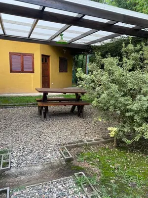 a wooden picnic table in front of a yellow house at Cabañas el Gauchito in Los Reartes