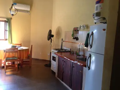 a kitchen with a white refrigerator and a table at Cabañas el Gauchito in Los Reartes
