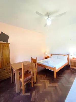 a bedroom with a bed and a table and a ceiling fan at Mirador del lago apart y cabañas- exclusivo adultos in Las Rabonas