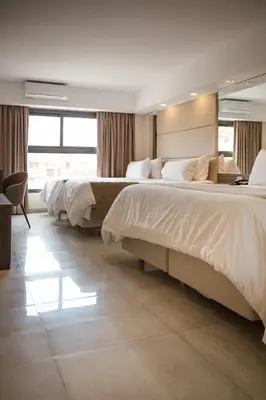 a hotel room with two beds and a desk at Eleton Resort & Spa in Villa Carlos Paz