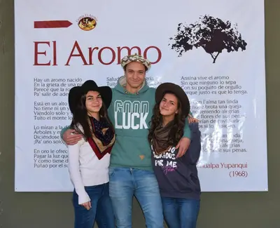 a man and two women standing in front of a poster at Granja El Aromo in Las Calles