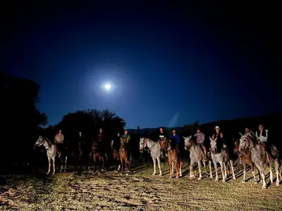 a group of people riding horses at night at Granja El Aromo in Las Calles