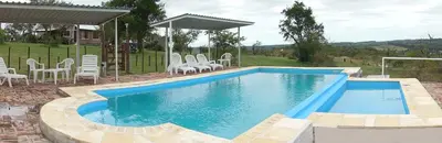 a swimming pool with chairs and a table at Cabañas del Peñasco in Alpa Corral