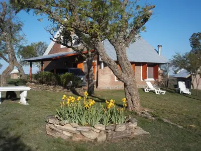 a house with a bench and flowers in front of it at Cabañas del Peñasco in Alpa Corral