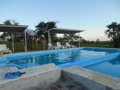 a woman is standing next to a swimming pool at Cabañas del Peñasco in Alpa Corral