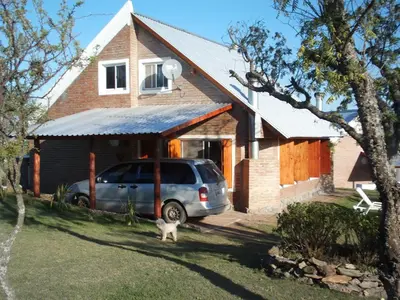 a car parked in front of a house with a cat at Cabañas del Peñasco in Alpa Corral