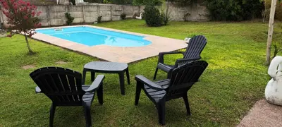 two chairs and a table in a yard with a pool at Chalet Carlos Paz in Villa Carlos Paz