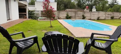 two chairs and a table next to a swimming pool at Chalet Carlos Paz in Villa Carlos Paz