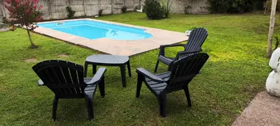 two black chairs and a table next to a pool at Chalet Carlos Paz in Villa Carlos Paz
