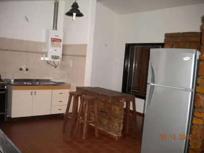 a kitchen with a refrigerator and a table with stools at Chalet Carlos Paz in Villa Carlos Paz