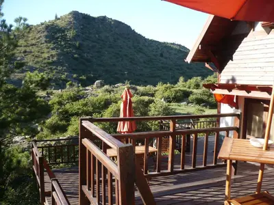 a deck with an umbrella and a table and a chair at Arroyo Escondido in La Cumbrecita