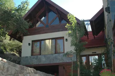 a house with a wooden roof and windows at Arroyo Escondido in La Cumbrecita