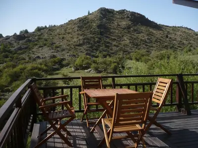 a table and chairs on a deck with a mountain at Arroyo Escondido in La Cumbrecita