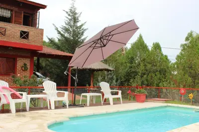 a group of chairs and an umbrella next to a pool at La Posada Del Poeta in Mina Clavero