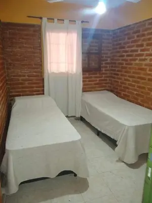 two beds in a room with a brick wall at La Posada Del Poeta in Mina Clavero