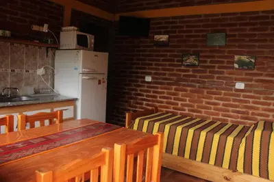 a kitchen with a table and chairs and a brick wall at La Posada Del Poeta in Mina Clavero