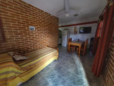 a bedroom with a brick wall and a bed and a table at La Posada Del Poeta in Mina Clavero