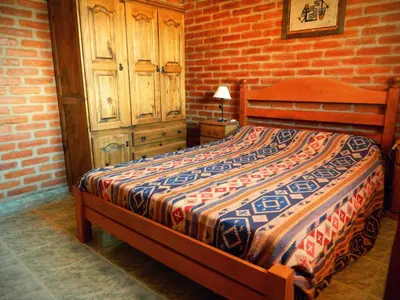 a bedroom with a bed and a brick wall at La Posada Del Poeta in Mina Clavero