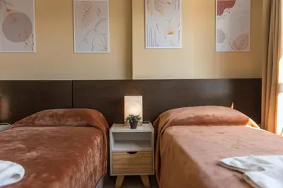 a room with two beds and a table with a lamp at Novum Suites in Cordoba