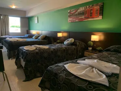 a hotel room with three beds and a green wall at Novum Suites in Cordoba