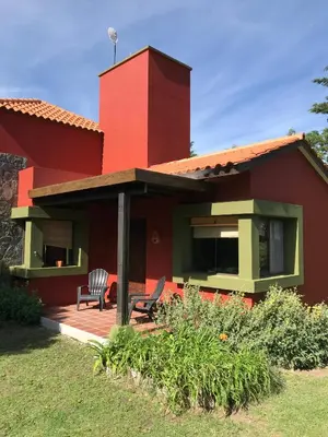 a red house with two chairs on a deck at Zolara Di Merlo in Merlo