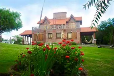 a large house with red flowers in front of it at Chalets Andalgala in Merlo