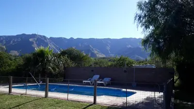 a swimming pool with two chairs next to a fence at Chalets Andalgala in Merlo