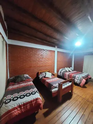 a room with two beds and a brick wall at Departamentos La Familia in Mina Clavero