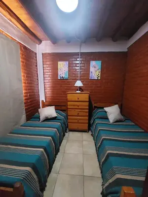 a room with two beds and a dresser in it at Departamentos La Familia in Mina Clavero