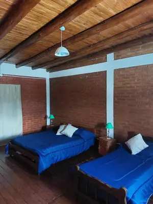 two beds in a room with a cross on the wall at Departamentos La Familia in Mina Clavero