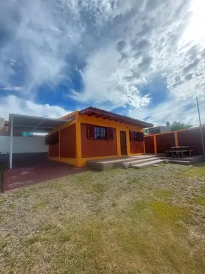 a yellow house with a picnic table in front of it at Departamentos La Familia in Mina Clavero