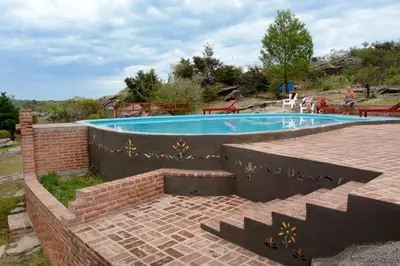a swimming pool with a brick wall around it at LA TOMA Complejo de Montaña - Cabañas y Habitaciones en Hosteria in Mina Clavero