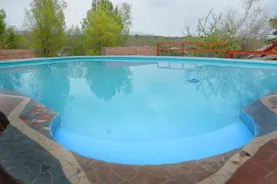 a large swimming pool with blue water in it at LA TOMA Complejo de Montaña - Cabañas y Habitaciones en Hosteria in Mina Clavero