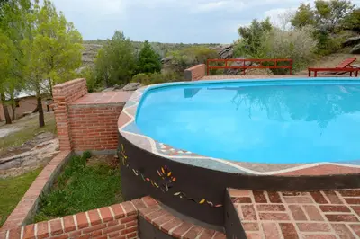 a large swimming pool with a brick retaining wall and a brick at LA TOMA Complejo de Montaña - Cabañas y Habitaciones en Hosteria in Mina Clavero