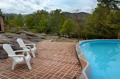 a patio with two chairs and a swimming pool at LA TOMA Complejo de Montaña - Cabañas y Habitaciones en Hosteria in Mina Clavero
