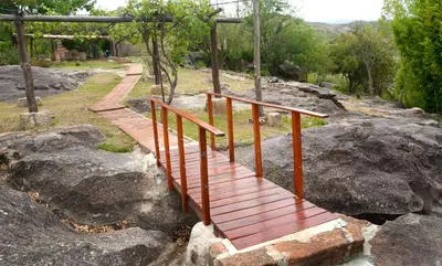 a wooden bridge on top of some rocks at LA TOMA Complejo de Montaña - Cabañas y Habitaciones en Hosteria in Mina Clavero
