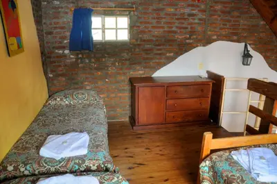 a bedroom with two beds and a brick wall at LA TOMA Complejo de Montaña - Cabañas y Habitaciones en Hosteria in Mina Clavero